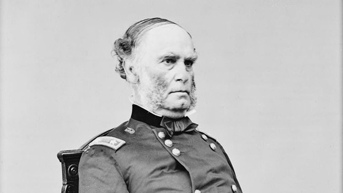 A black and white photo of an older gentleman, dressed in a union officers jacket, sitting in a chai